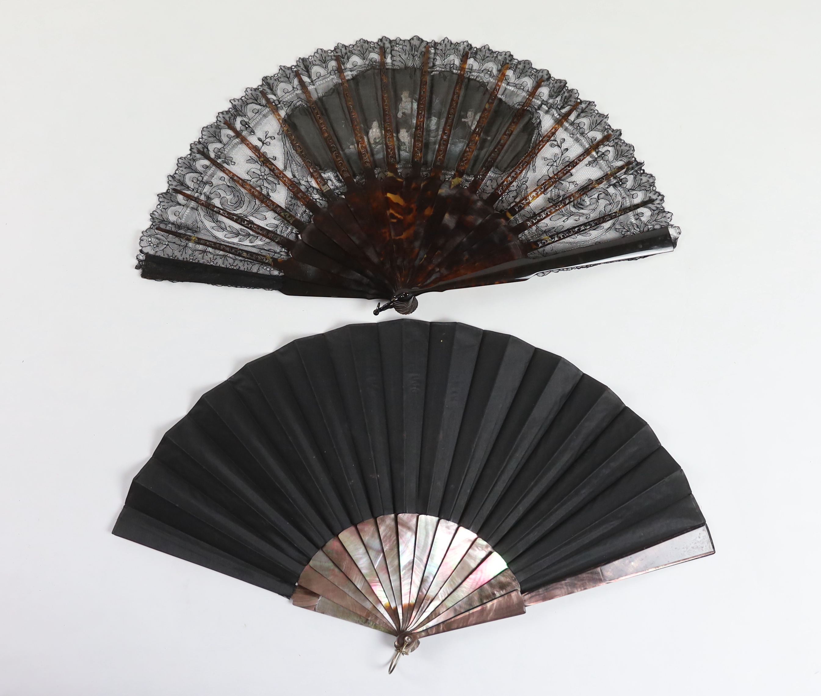 A late Victorian Chantilly black lace and tortoiseshell fan with a central painted cartouche and a mother of pearl and hand painted fairy and cherub fan, indistinctly signed